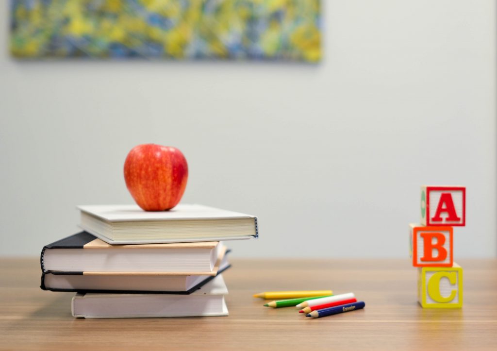 An image of school books, blocks, and an apple.